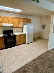 A kitchen with a black stove top oven and white refrigerator.