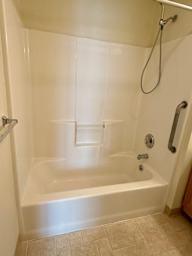 A white bathtub with a shower head and a hose.