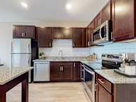 A kitchen with brown cabinets and a granite countertop.