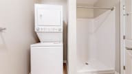 A white tankless water heater with a control panel sits next to a white shower stall.