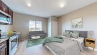 A bedroom with a bed, couch, and a painting on the wall.