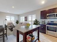 A kitchen with a granite countertop and a dining table with chairs.