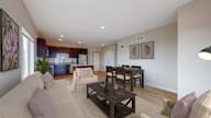 A living room with a couch, chairs, and a dining table.