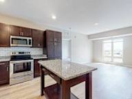 A kitchen with a granite countertop and stainless steel appliances.