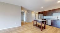A kitchen with wooden floors and a stainless steel refrigerator.