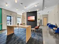 A conference room with a long table, chairs, and a television screen.