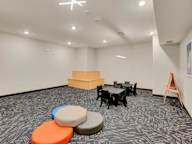 A room with a carpeted floor, a table with chairs, and a podium.