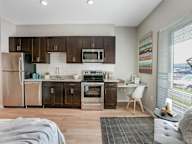 A modern kitchen with dark brown cabinets and stainless steel appliances.