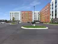 A parking lot in front of a multi-story apartment building.
