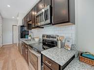 A kitchen with a black refrigerator, stove, and microwave.