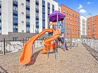 A playground with a purple slide and orange slide.