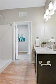 A bathroom with a sink, mirror, and a doorway leading to another room.