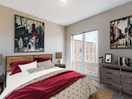 A bedroom with a bed, nightstand, and two paintings on the wall.