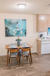 a dining room with a table and chairs and a painting on the wall