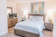 a bedroom with a bed and two dressers and a tv