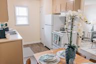 a kitchen and dining room with white appliances and a table with flowers