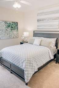 a bedroom with a bed with a white comforter and pillows on it