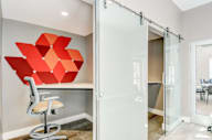 a room with a desk and a chair and a large red painting on the wall