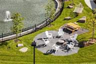a park with tables and chairs near a body of water