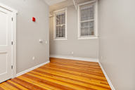 A room with a wooden floor and a window with blinds.