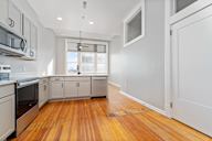 A kitchen with wooden floors and white cabinets.