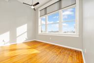 Room with a ceiling fan and a large window showing a blue sky with clouds.