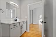 A bathroom with a sink, mirror, and wooden floor.