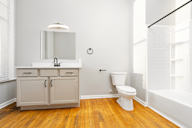A white bathroom with a wooden floor and a white toilet.