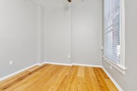 A room with wooden flooring and a window with blinds.