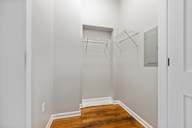 A white closet with a wooden floor and a white door.