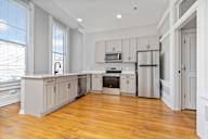 A kitchen with wooden floors and white cabinets.