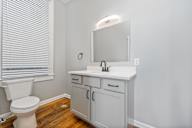 A white bathroom with a toilet, sink, and mirror.
