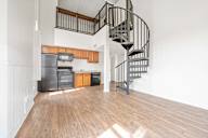 A spiral staircase in a room with wooden floors and white walls.