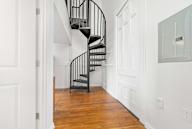 A black spiral staircase in a white hallway.