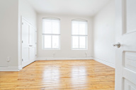 A room with wooden floors and two windows.