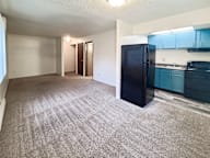 A black refrigerator sits in a kitchen with blue cabinets.