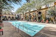 a swimming pool with lounge chairs under palm tress