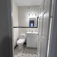 A white toilet is in a bathroom with a sink and mirror.