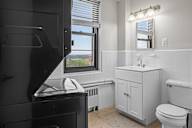 A bathroom with a toilet, sink, and a window.