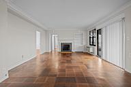 A large empty room with a fireplace and wooden floors.