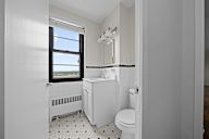 A white bathroom with a toilet, sink, and window.