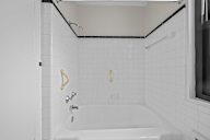 A white bathroom with a white tub and white tiles.