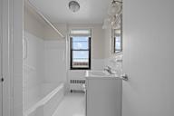 A white bathroom with a window and a bathtub.