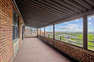 A balcony with a wooden floor and brick walls.