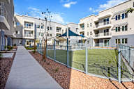 A tennis court is enclosed by a fence in a residential area.