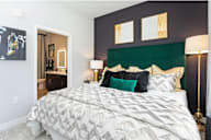 A bed with a white comforter and a black and white pillow is in the center of the image.