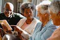 a group of people sitting on a couch looking at a tablet