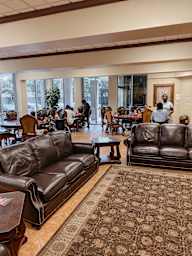 a large room with leather couches and tables and people sitting at tables in the background