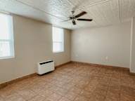 an empty room with a ceiling fan and a radiator