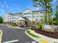 Active Adult Community with an exterior view of an apartment building with a courtyard and benches